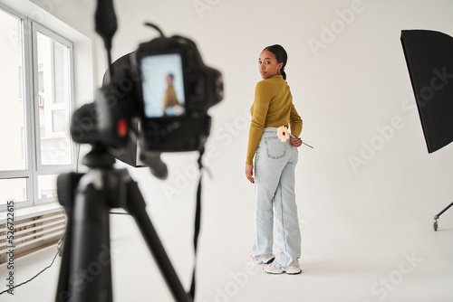 Multiracial professional model standing with camomile at the studio and posing to the camera photo