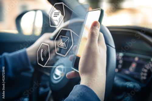 Fototapeta Naklejka Na Ścianę i Meble -  Drive a car and use smartphone. Reading messages holding a cell phone while driving. Transportation and new automotive technology concept. Infotainment, navigation, multimedia communication device