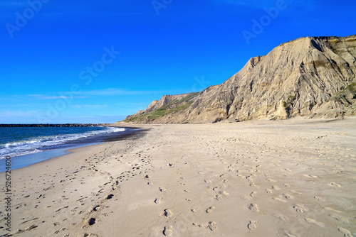 Cliff and empty beach at Ferring on the North Sea coast of Denmark in perfect evening light in front of a blue sky with some clouds at the horizon, high quality image