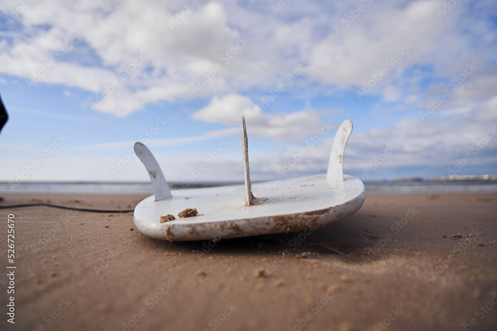 Surfboard laying on the sandy beach with bright cloudy sky and horizontal line of seascape Surfboard laying on the sandy beach with bright cloudy sky and horizontal line of seascape