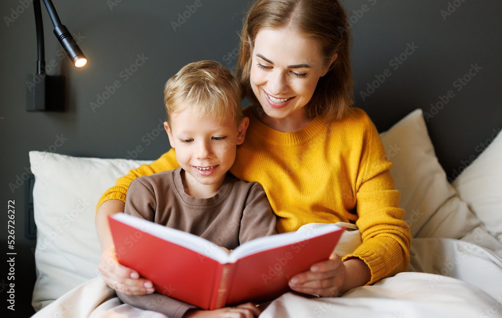 Happy mother and son reading book together on bed Happy mother and son reading book together on bed