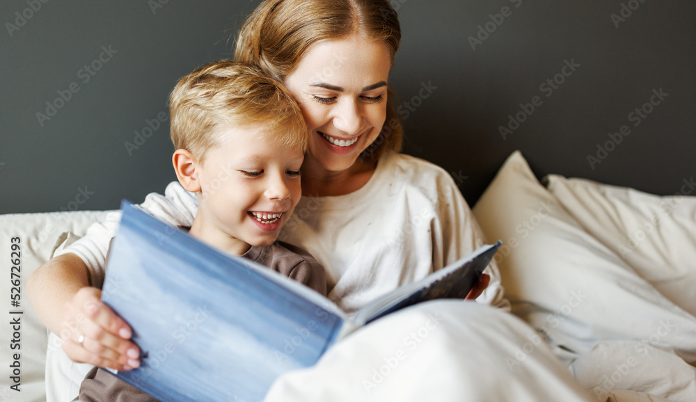 Happy mother and son reading book together on bed Happy mother and son reading book together on bed