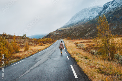 Man traveling solo in Norway outdoor walking on the road autumn mountains view vacations healthy lifestyle adventure trip getaway