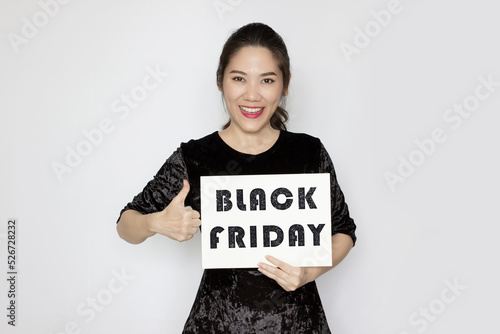 Asian beautiful woman holding black Friday paper ad and make thumbs up hand sign with smile and happy.