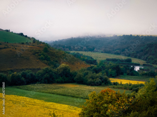 Beautiful fog over fields and hills on a summer morning. A plain under gentle hills. Colorful landscape.