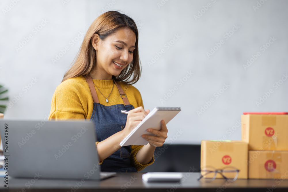Asian woman look like india girl working SME business at workplace at home. use laptop checking customer order online shipping boxes, freelance SME entrepreneur online business idea. Asian woman look like india girl working SME business at workplace at home. use laptop checking customer order online shipping boxes, freelance SME entrepreneur online business idea.
