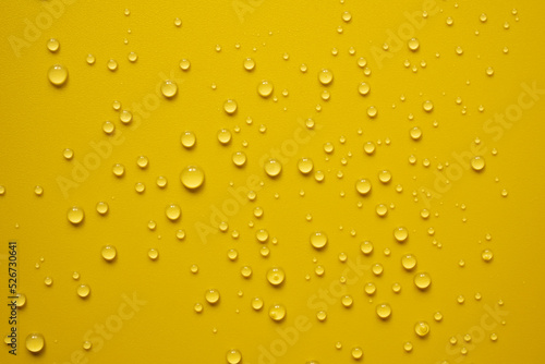 Lot of small drops on a yellow surface, splashed water. Abstract background. Top view. 