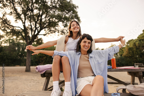 Happy young caucasian women have fun, spend free time together in nature. Brunettes wear T-shirts, shirts and shorts. Summer vacation concept. #526733431