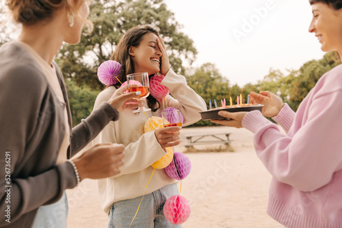 Cheerful young caucasian ladies enjoy spending time on holiday in honor of friend nature. Brunettes drink drinks, wear sweaters. Lifestyle concept