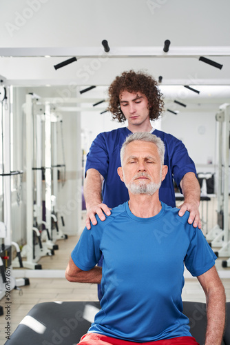 Male physiotherapist working on elderly man's tension his shoulders