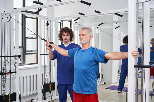 Senior male doing trx training during visit to physiotherapist