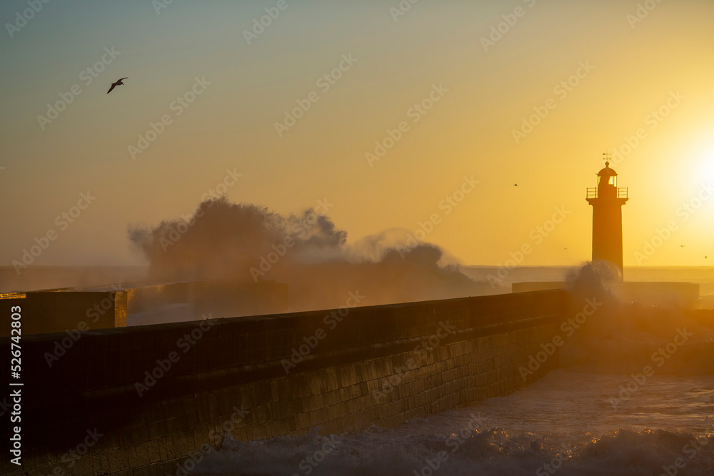Wave on the lighthouse in the background on the golden sunset. Atlantic, Porto, Portugal. Wave on the lighthouse in the background on the golden sunset. Atlantic, Porto, Portugal.