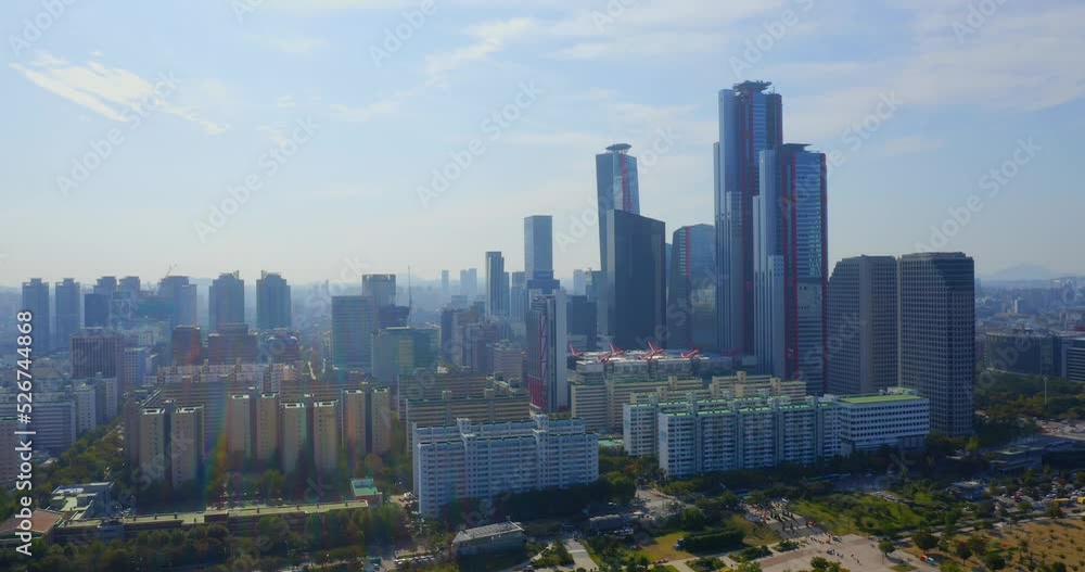 Drone shot traveling forward above the Han river toward the a business district with skyscrapers in Seoul city during the day. a park is visible on the foreground. Drone shot traveling forward above the Han river toward the a business district with skyscrapers in Seoul city during the day. a park is visible on the foreground.