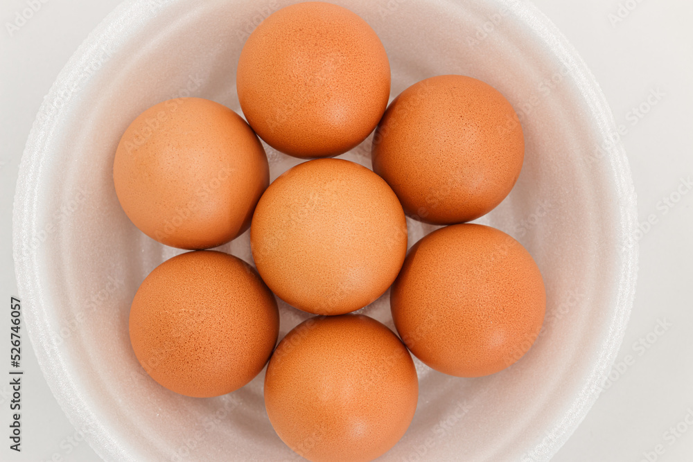 Seven raw chicken eggs in a styrofoam cup with white background. Seven raw chicken eggs in a styrofoam cup with white background.
