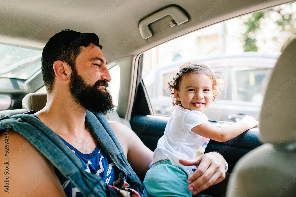 Father with little daughter sitting in a car on streets in city of Tbilisi in the capital of Georgia on sunny spring day. Dad and girl travel on excursion in old town. Father with little daughter sitting in a car on streets in city of Tbilisi in the capital of Georgia on sunny spring day. Dad and girl travel on excursion in old town.