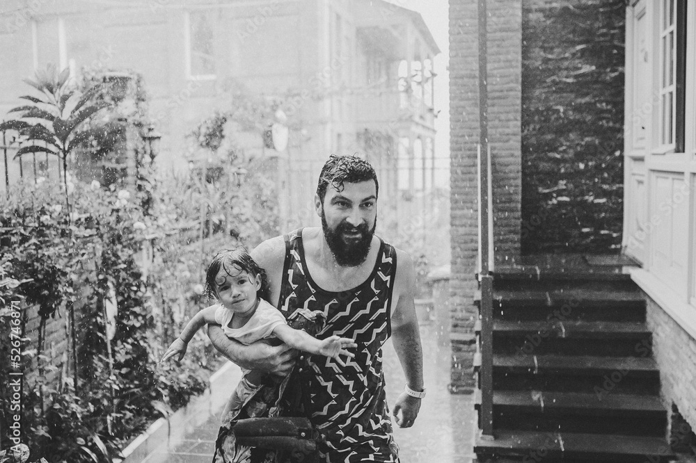 Father walking with little daughter outdoors, on streets in old town of Tbilisi in capital of Georgia on spring rainy day. Dad, girl running away, in the rain in city. Tourist. black and white photo.