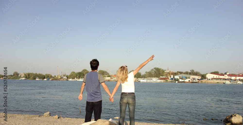 couple holding hands on a beach near danube river in a sunny summer day couple holding hands on a beach near danube river in a sunny summer day