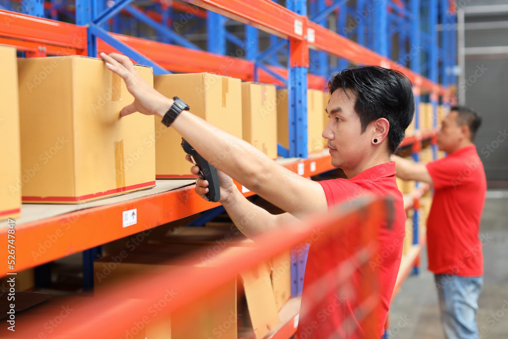 Obraz premium Group of warehouse workers asian men scanning barcode on large box package for delivery to production stock and inventory in retail warehouse logistics, distribution center