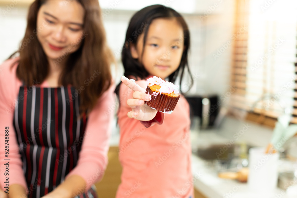 Preschool kid person make Cake cooking in kitchen, young girl prepare decoration pretty with fun educate on cupcake for birthday sister. Cream mess on curly hair face and mouth, feel happy, copy space