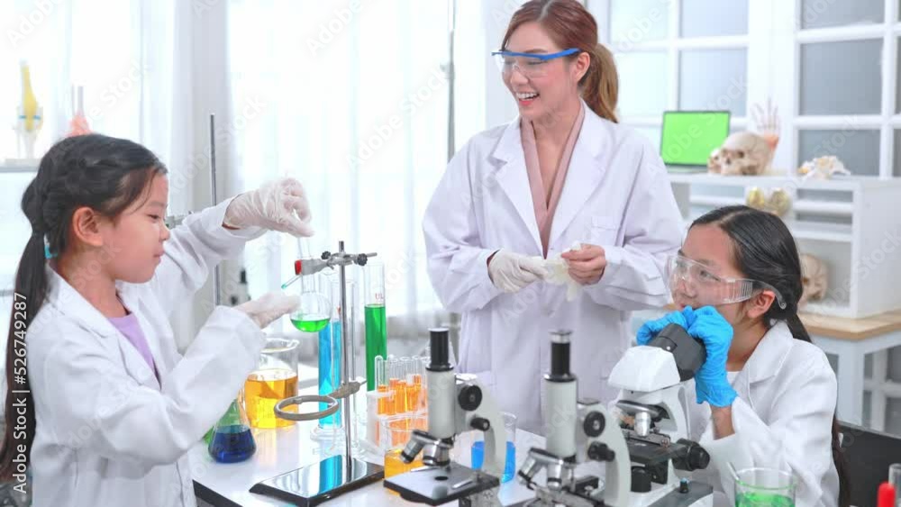 Beautiful Asian female teacher and female student scientist conducting an experiment in lab Beautiful Asian female teacher and female student scientist conducting an experiment in lab