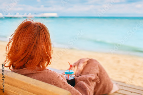 Photographie Woman is resting on the sea beach and admiring the ocean landscape