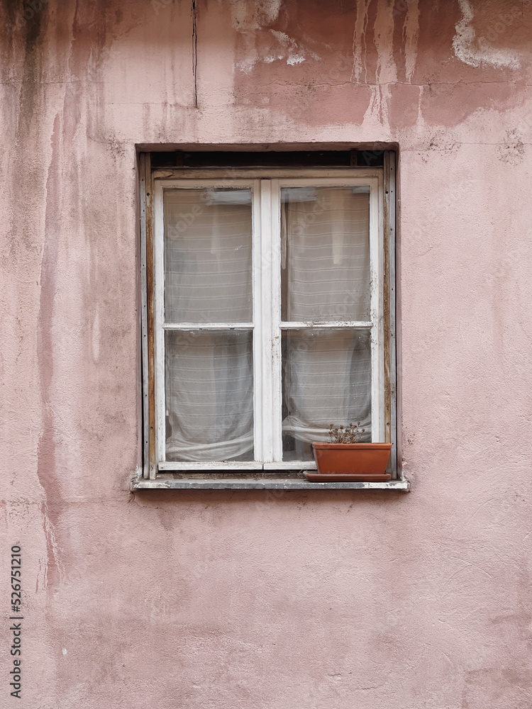 Window with wooden shutters, neutral pink wall. Traditional European old town building. Old ancient historic architecture