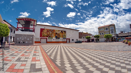 Buildings around a park tiled in a checkerboard pattern, in Cotacachi, Ecuador, taken with a fisheye lens photo