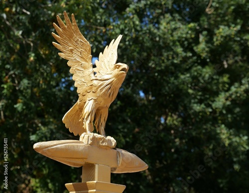 Reproduction dorée d'un aigle de Jupiter dressé sur un foudre et aux ailes déployées, au sommet d'une enseigne de l'armée romaine, sur fond de végétation photo
