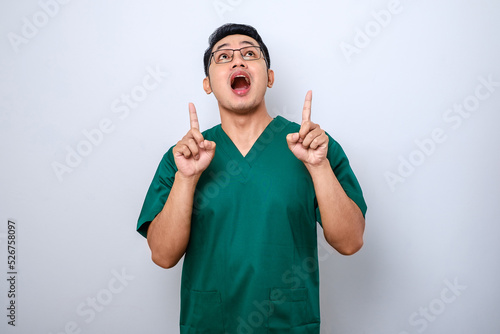 Bilde på lerret Amazed and impressed asian male nurse, doctor in scrubs pointing fingers up and