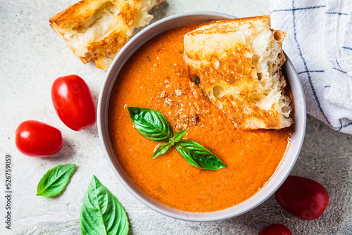 Traditional gaspacho in gray bowl. Summer tomato soup with basil. photo