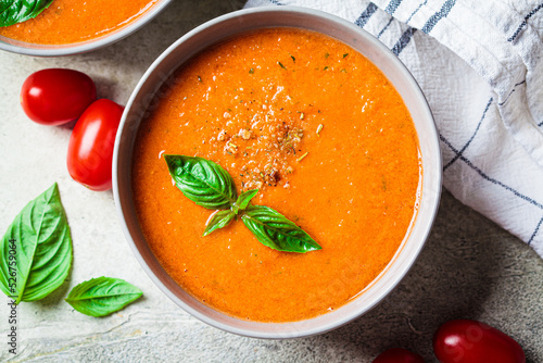 Traditional gaspacho in gray bowl. Summer tomato soup with basil.