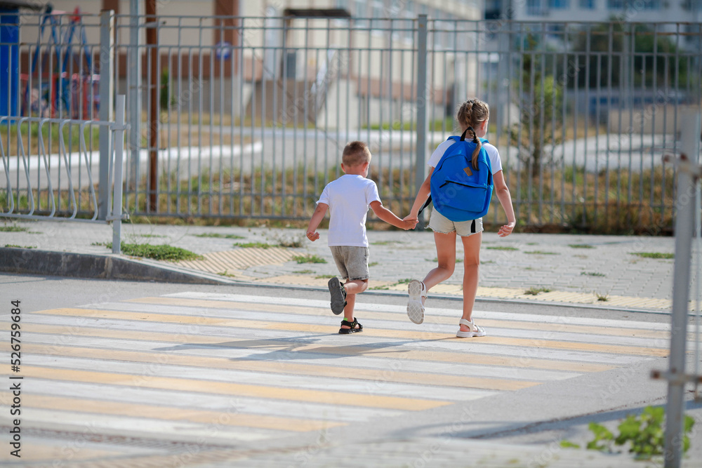 Brother and sister run across a pedestrian crossing. Children Run along