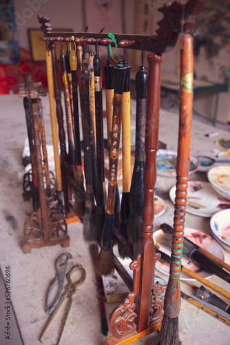 Paint brushes of a traditional chinese painter artist hanging on the table together with the oil paints
