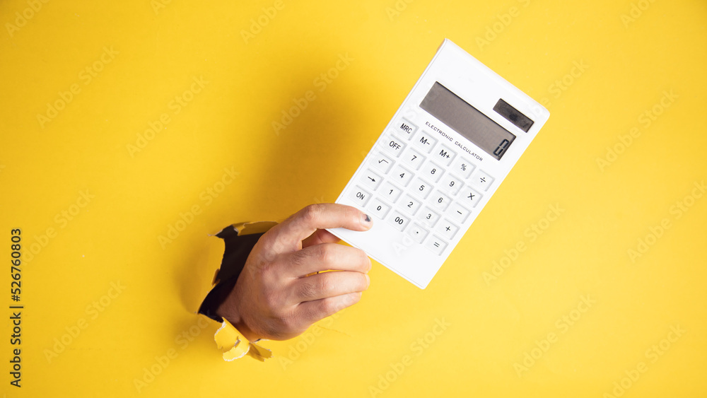 male hand calculator a yellow background - obrazy, fototapety, plakaty 