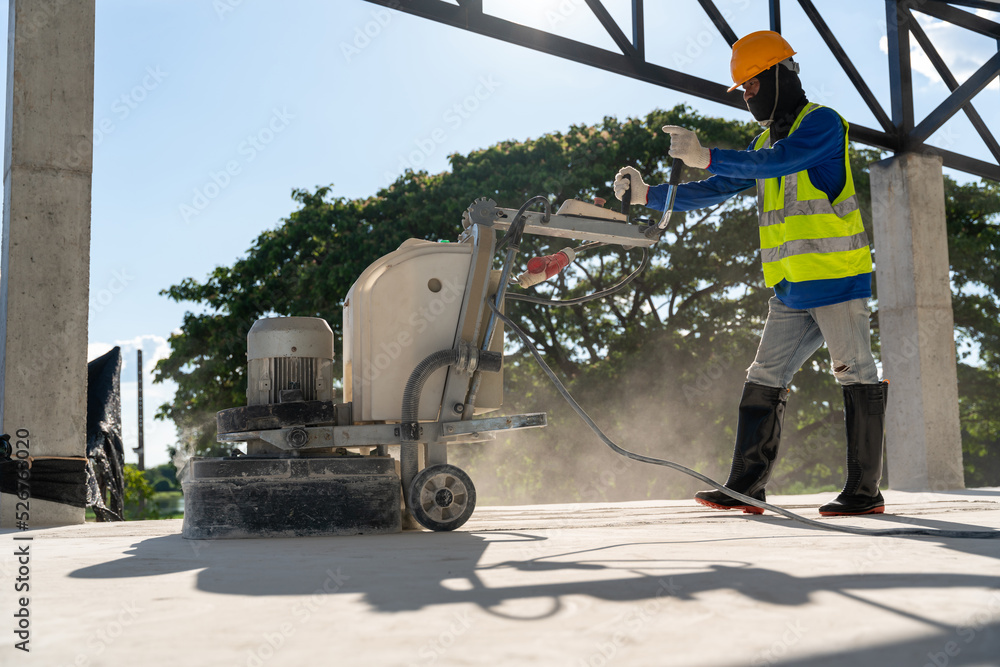 A man wear safety works with grinding machine for concrete floor at construction site. Concrete floors.