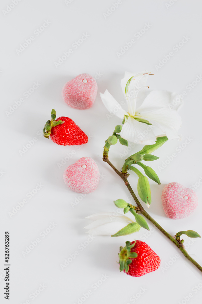 Branch composition with flowers, strawberries and candies. Food styling. Spring comfort food composition. Branch composition with flowers, strawberries and candies. Food styling. Spring comfort food composition.