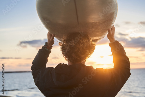 Photography Man standing with long surfing board at his head while waiting on high waves at