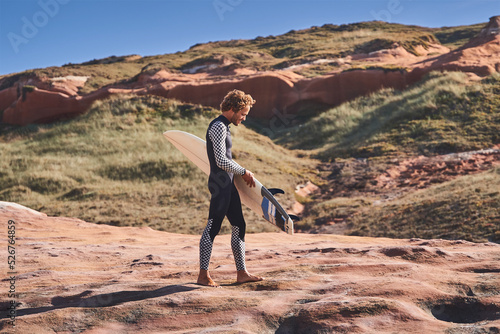 Strong young surf man walking calmly at the beach with surfboard