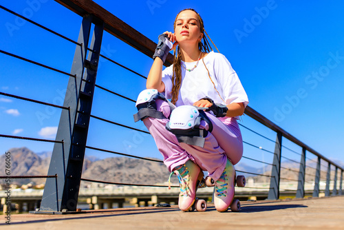 Fototapeta Naklejka Na Ścianę i Meble -  Happy woman with long blonde braids hair on the roller-skate in the park beach and mountain background