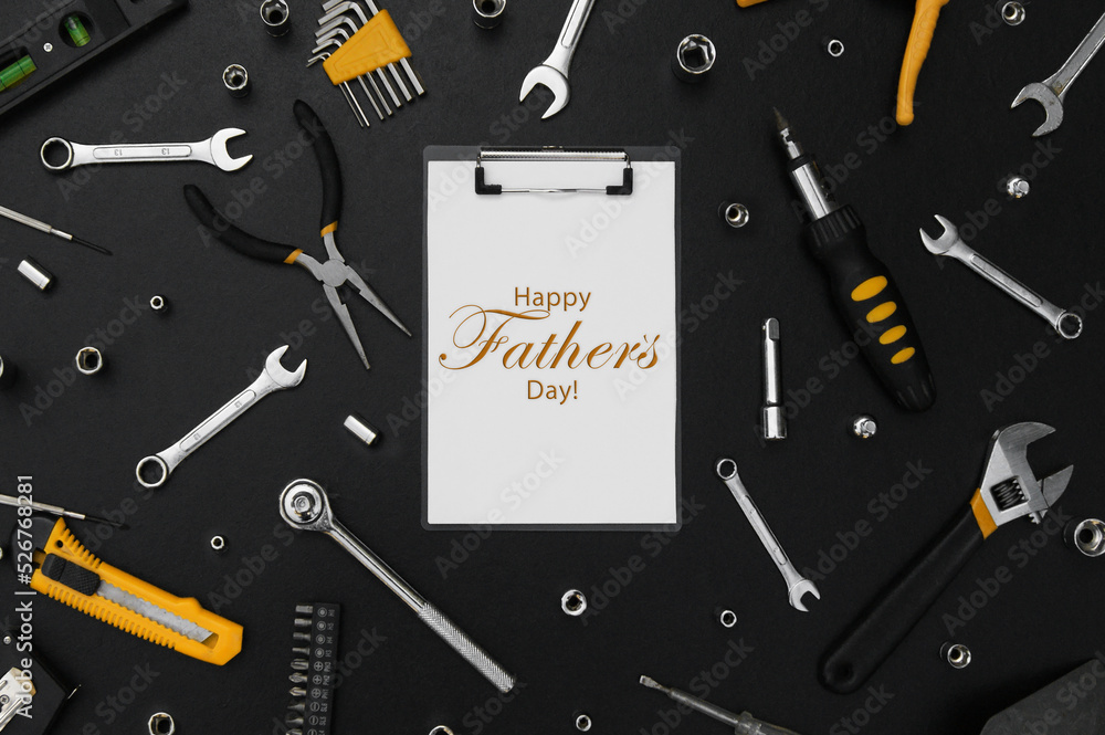 Lettering Happy Father's Day with many different tools for repair work on a black table. Lettering Happy Father's Day with many different tools for repair work on a black table.