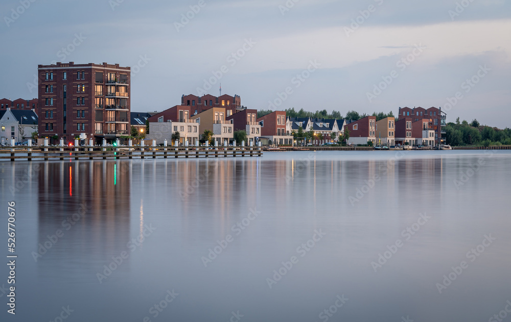 Modern residential neighbourhood along the lake in the village of Spaarndam by sunset
