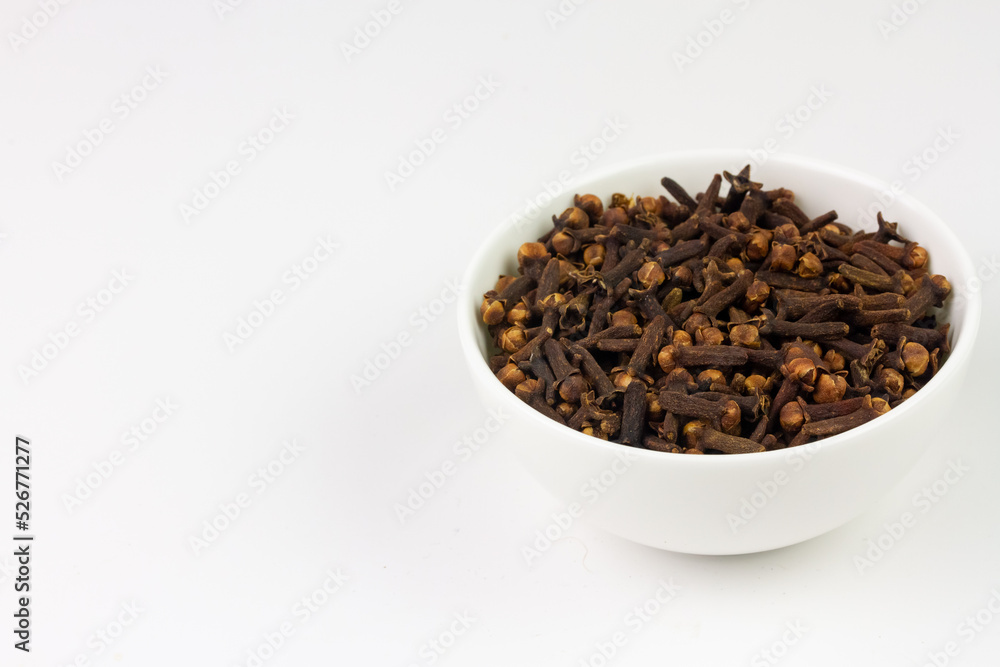 Cloves in white bowl isolated on white background, copy space. Herbal cloves have a fragrant and spicy flavor. Cloves in white bowl isolated on white background, copy space. Herbal cloves have a fragrant and spicy flavor.