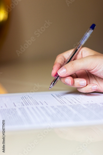 The hand holds a ballpoint pen in its hand and signs the document