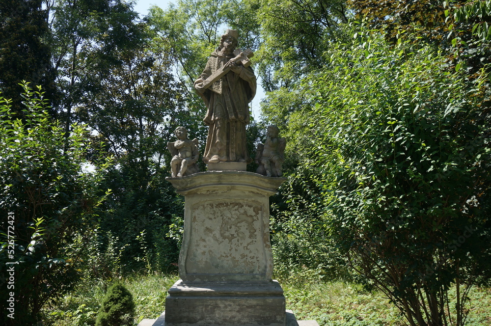 St. John of Nepomuk' statue. Saint is depicted in a clergyman's clothes, he hold the crucifix in front of him with both hands. Czeladz, Poland.