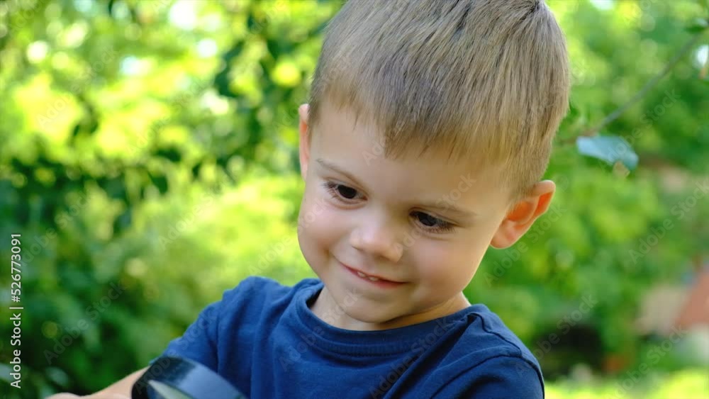 Children look at a snail with a magnifying glass, selective focus. Children look at a snail with a magnifying glass, selective focus.