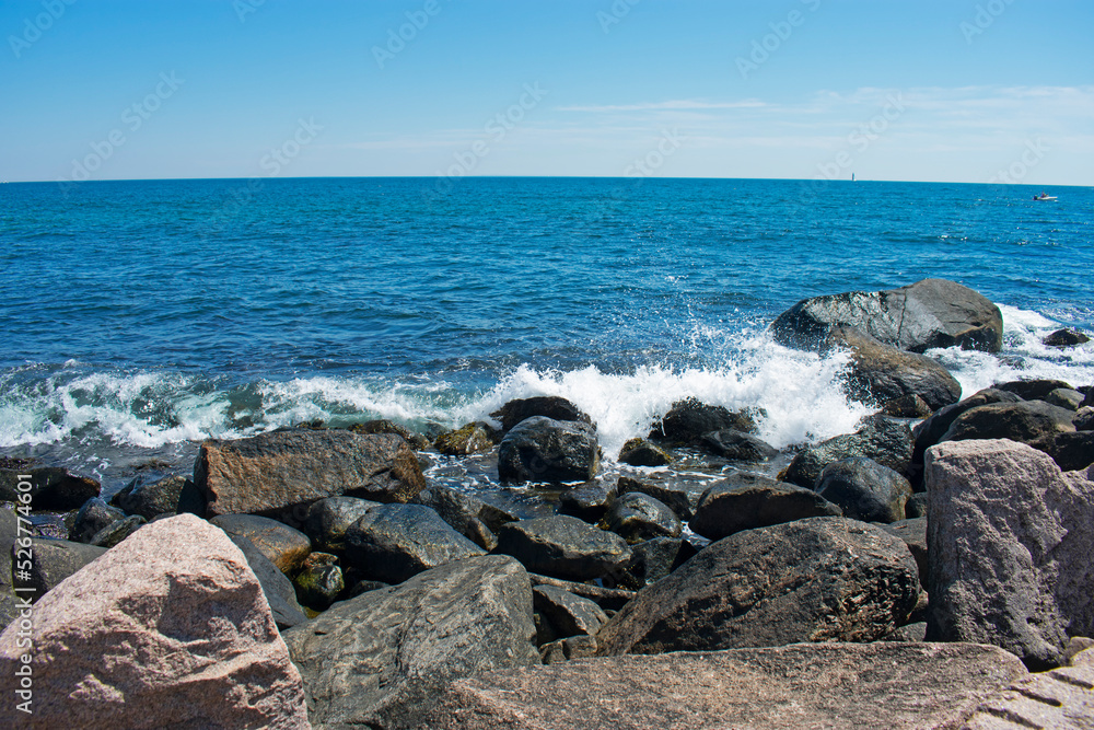 Waves crashing into rocky shoreline in Westerly, Rhode Island, on a sunny day with blue skies -05