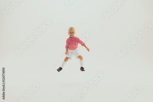 Portrait of little smiling boy, child in pink checkered shirt playing, posing, having fun isolated over grey studio background