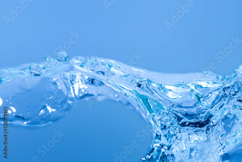 Blue water splashes the wave surface with bubbles of air on white background.
