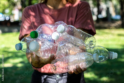 Photography Close up on a pile of plastic bottles held by a young caucasian woman in a park,