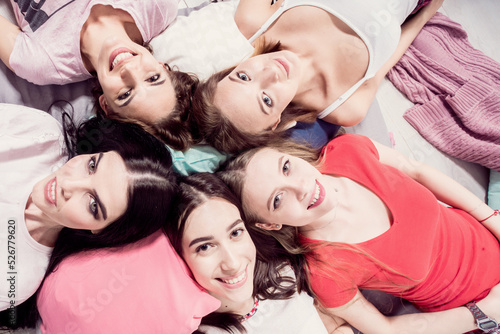 A circle of beautiful girls faces on bed.